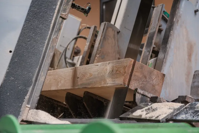 Ein Holzbalken wird vom Sägeblatt geschnitten, dabei fällt Sägemehl