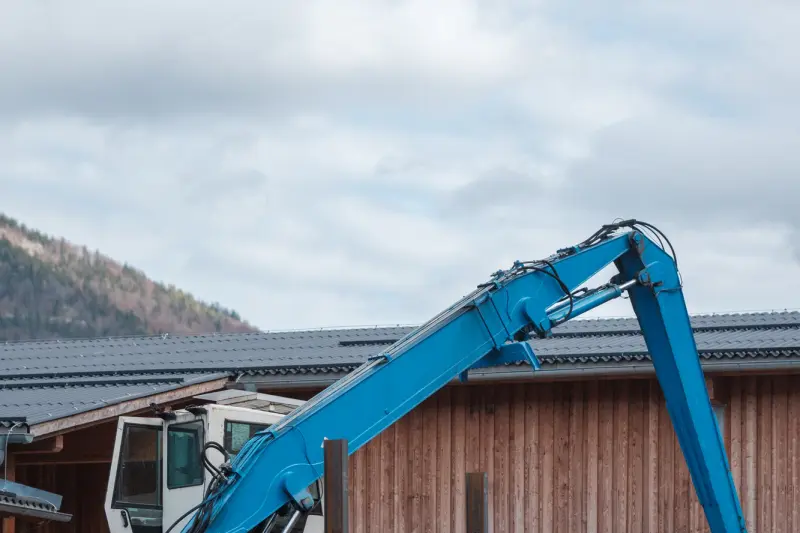 Materialumschlagbagger Fuchs MHL 430 vor einer Lagerhalle des Sägewerks