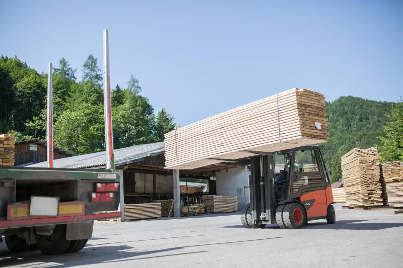 Gabelstapler transportiert ein Paket Schnittholz über den Lagerplatz
